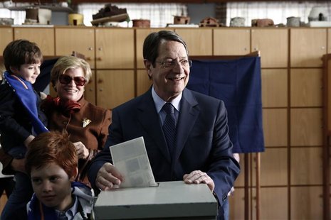 Cyprus presidential candidate Nicos Anastasiades (C) of the right wing Democratic Rally party casts his ballot as his wife Andriana and his Cyprus presidential candidate Nicos Anastasiades (C) of the right wing Democratic Rally party casts his ballot as his wife Andriana and his