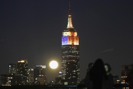 A full moon rises behind the Empire State Building and the skyline of New York, as people watch from a park along the Hudson River in Hoboke A full moon rises behind the Empire State Building and the skyline of New York, as people watch from a park along the Hudson River in Hoboke