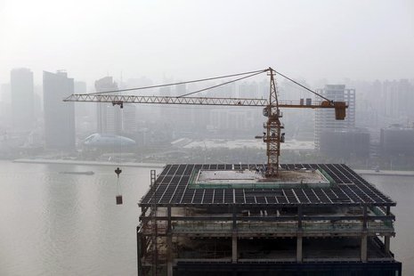 Construction workers are seen on a high rise office building site on the Pudong River bank at the new financial district of Pudong in Shangh Construction workers are seen on a high rise office building site on the Pudong River bank at the new financial district of Pudong in Shangh
