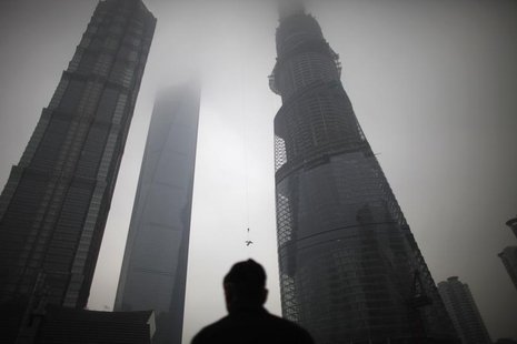 A man watches a construction crane lift a piece of steel at the Shanghai Tower (R) at the financial district of Pudong in Shanghai January 2 A man watches a construction crane lift a piece of steel at the Shanghai Tower (R) at the financial district of Pudong in Shanghai January 2