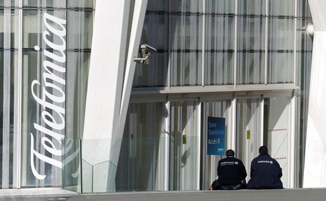 Workers rest sitting next to Telefonica's tower entrance in Barcelona January 30, 2013. REUTERS/Albert Gea Workers rest sitting next to Telefonica's tower entrance in Barcelona January 30, 2013. REUTERS/Albert Gea