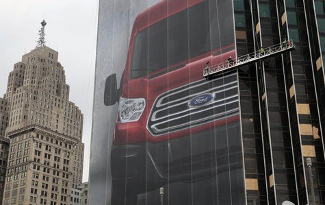 Workers hang a Ford Motor banner on the side of a building across from Cobo Center in advance of the media preview of the North American Int Workers hang a Ford Motor banner on the side of a building across from Cobo Center in advance of the media preview of the North American Int