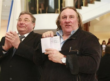 French film star Gerard Depardieu (R) shows his passport with residency permit as Vladimir Volkov, head of the Republic of Mordovia, applaud French film star Gerard Depardieu (R) shows his passport with residency permit as Vladimir Volkov, head of the Republic of Mordovia, applaud