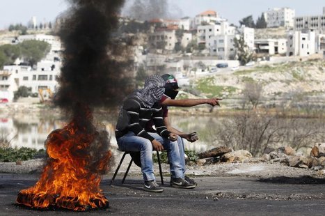 Palestinians hold stones as they sit next to a burning tyre during clashes with Israeli troops outside Israel's Ofer military prison near th Palestinians hold stones as they sit next to a burning tyre during clashes with Israeli troops outside Israel's Ofer military prison near th