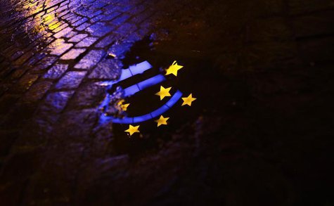 The Euro sculpture is partially reflected in a puddle on a cobblestone pavement in front of the headquarters of the European Central Bank (E The Euro sculpture is partially reflected in a puddle on a cobblestone pavement in front of the headquarters of the European Central Bank (E