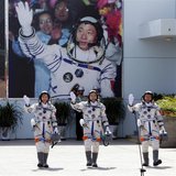 Chinese astronauts Jing Haipeng (C), Liu Wang (R) and Liu Yang, China's first female astronaut, wave in front of a picture of the first astr