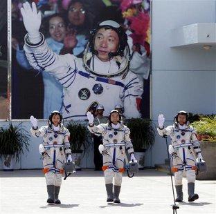 Chinese astronauts Jing Haipeng (C), Liu Wang (R) and Liu Yang, China's first female astronaut, wave in front of a picture of the first astr Chinese astronauts Jing Haipeng (C), Liu Wang (R) and Liu Yang, China's first female astronaut, wave in front of a picture of the first astr
