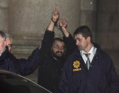 Ali Charaf Damache, also known by the alias "Black Flag," is accompanied by Irish law enforcement officials as he appears at Waterford Distr Ali Charaf Damache, also known by the alias "Black Flag," is accompanied by Irish law enforcement officials as he appears at Waterford Distr