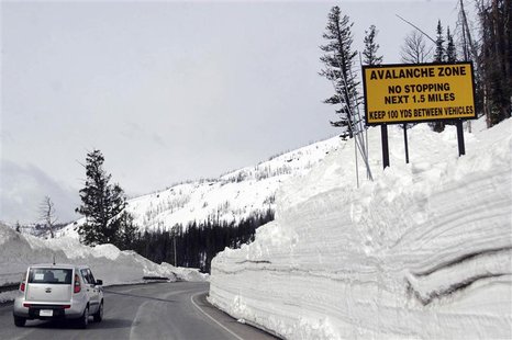 A car travels the newly plowed east entrance road over Sylvan Pass in Yellowstone National Park shortly after the park opened in this photo A car travels the newly plowed east entrance road over Sylvan Pass in Yellowstone National Park shortly after the park opened in this photo