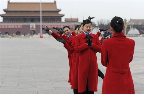 Hotel guides pose for a photograph in front of the giant portrait of the late chairman Mao Zedong during a pre-session of the Chinese People Hotel guides pose for a photograph in front of the giant portrait of the late chairman Mao Zedong during a pre-session of the Chinese People