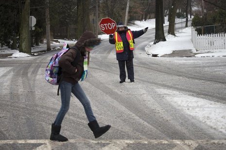 A guard helps a student cross an intersection in Pelham, New York February 8, 2013. REUTERS/Adrees Latif A guard helps a student cross an intersection in Pelham, New York February 8, 2013. REUTERS/Adrees Latif
