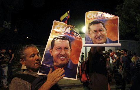 Supporters of Venezuela's President Hugo Chavez show pictures of him as they react to the announcement of his death outside the Venezuelan E Supporters of Venezuela's President Hugo Chavez show pictures of him as they react to the announcement of his death outside the Venezuelan E