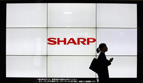 A woman walks past the Sharp Corp's Logo at a train station in Tokyo March 6, 2013. Samsung Electronics Co is set to invest $110 million in A woman walks past the Sharp Corp's Logo at a train station in Tokyo March 6, 2013. Samsung Electronics Co is set to invest $110 million in