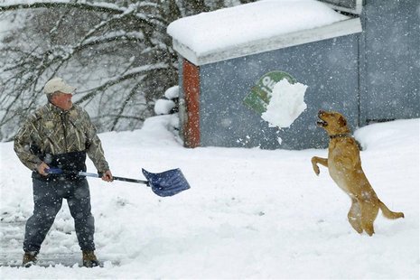 Bill Groves plays with his dog Red while shovelling snow during a massive blizzard near Mt. Jackson, Virginia March 6, 2013. REUTERS/Gary Ca Bill Groves plays with his dog Red while shovelling snow during a massive blizzard near Mt. Jackson, Virginia March 6, 2013. REUTERS/Gary Ca