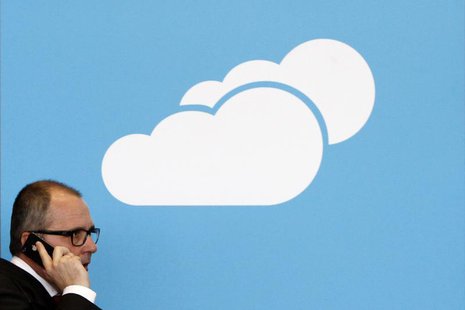 A visitor uses his mobile phone as he walks past the Microsoft booth with a logo for cloud computing software application at the CeBit compu A visitor uses his mobile phone as he walks past the Microsoft booth with a logo for cloud computing software application at the CeBit compu