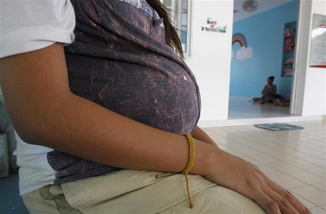 An unnamed 18-year-old teenager, who is eight months pregnant, rests outside her room at the Association for the Promotion of the Status of An unnamed 18-year-old teenager, who is eight months pregnant, rests outside her room at the Association for the Promotion of the Status of