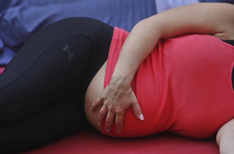 A pregnant woman touches her stomach as people practice yoga on the morning of the summer solstice in New York's Times Square June 20, 2012. A pregnant woman touches her stomach as people practice yoga on the morning of the summer solstice in New York's Times Square June 20, 2012.