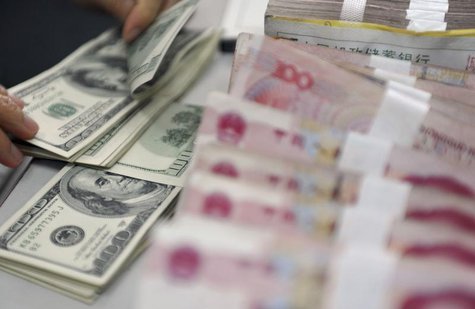 A clerk counts U.S. dollar banknotes after counting Chinese 100 Yuan banknotes at a branch of the Agricultural Bank of China in Qionghai, Ch A clerk counts U.S. dollar banknotes after counting Chinese 100 Yuan banknotes at a branch of the Agricultural Bank of China in Qionghai, Ch