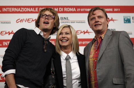 Actress Olivia Newton John (C) smiles as she poses with director Stephan Elliot (R) and actor Kris Marshall during a photocall of their movi Actress Olivia Newton John (C) smiles as she poses with director Stephan Elliot (R) and actor Kris Marshall during a photocall of their movi