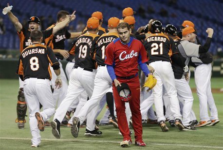 Cuba's pitcher Diosdany Castillo (C) walks off the field as Netherlands' players celebrate after defeating Cuba at the World Baseball Classi Cuba's pitcher Diosdany Castillo (C) walks off the field as Netherlands' players celebrate after defeating Cuba at the World Baseball Classi