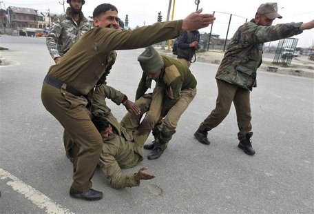 Indian paramilitary soldiers gesture as their injured colleague lie on the ground during a gunfight in Srinagar March 13, 2013. Two militant Indian paramilitary soldiers gesture as their injured colleague lie on the ground during a gunfight in Srinagar March 13, 2013. Two militant