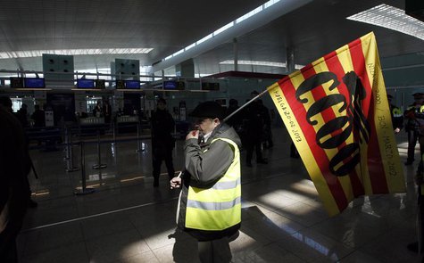 A man holding a Comisiones Obreras (CCOO) trade union flag walks past Iberia's check-in desk during an Iberia workers strike at Terminal 1 o A man holding a Comisiones Obreras (CCOO) trade union flag walks past Iberia's check-in desk during an Iberia workers strike at Terminal 1 o