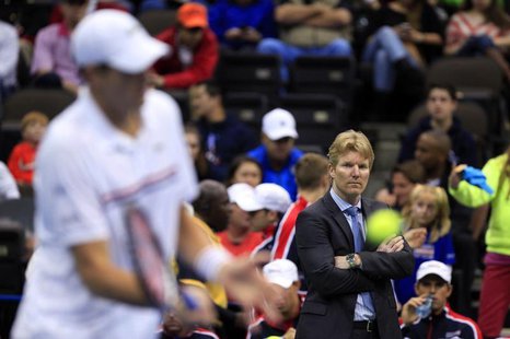 U.S. team captain Jim Courier (R) watches as John Isner practises before his match against Brazil's Thomaz Bellucci during the Davis Cup wor U.S. team captain Jim Courier (R) watches as John Isner practises before his match against Brazil's Thomaz Bellucci during the Davis Cup wor
