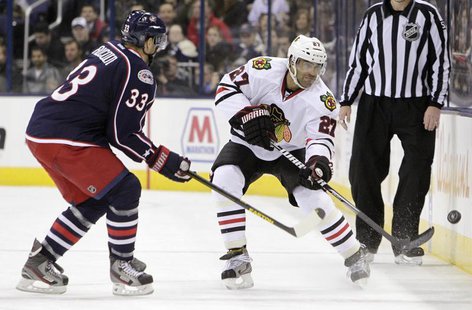 Chicago Blackhawks' Johnny Oduya (27) clears the puck as Columbus Blue Jackets' Adrian Aucoin (33) defends during their NHL hockey game in C Chicago Blackhawks' Johnny Oduya (27) clears the puck as Columbus Blue Jackets' Adrian Aucoin (33) defends during their NHL hockey game in C