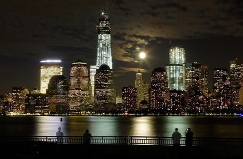 The moon rises behind the skyline of New York's Lower Manhattan and One World Trade Center as people stand along the Hudson River in Jersey The moon rises behind the skyline of New York's Lower Manhattan and One World Trade Center as people stand along the Hudson River in Jersey