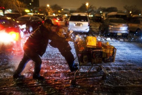 A child hangs on to shopping cart as his father pushes as they make their way to their car during a winter storm at Jersey City in New Jerse A child hangs on to shopping cart as his father pushes as they make their way to their car during a winter storm at Jersey City in New Jerse
