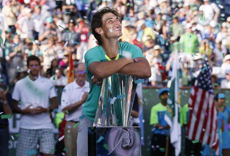 Rafael Nadal of Spain smiles as he leans on his trophy, while confetti flutters in the air, after he defeated Juan Martin Del Potro (rear L) Rafael Nadal of Spain smiles as he leans on his trophy, while confetti flutters in the air, after he defeated Juan Martin Del Potro (rear L)