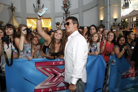 Judge Simon Cowell poses with a fan at the season two premiere of the television series "The X Factor" at Grauman's Chinese theatre in Holly Judge Simon Cowell poses with a fan at the season two premiere of the television series "The X Factor" at Grauman's Chinese theatre in Holly