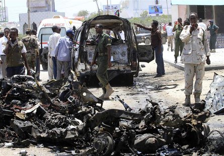 A Somali soldier uses his mobile phone to record the wreckage of vehicles at the scene of an explosion near the presidential palace in Somal A Somali soldier uses his mobile phone to record the wreckage of vehicles at the scene of an explosion near the presidential palace in Somal