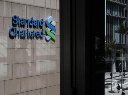 A man walking past a foot bridge leading to the Standard Chartered main branch is reflected on a window glass in Hong Kong March 5, 2013. RE A man walking past a foot bridge leading to the Standard Chartered main branch is reflected on a window glass in Hong Kong March 5, 2013. RE