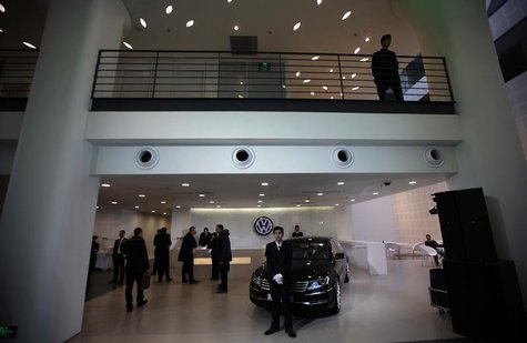 Security personnel keep guard beside a Volkswagen vehicle during a media tour at the opening ceremony of a new Audi China building in Beijin Security personnel keep guard beside a Volkswagen vehicle during a media tour at the opening ceremony of a new Audi China building in Beijin