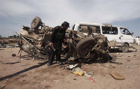 A security official inspects a damaged vehicle at the site of a bomb attack nearJalozai camp in Nowshera district, northwestern Pakistan Mar A security official inspects a damaged vehicle at the site of a bomb attack nearJalozai camp in Nowshera district, northwestern Pakistan Mar