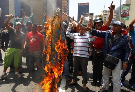 Supporters of the late President Hugo Chavez burn a flag with Capriles' campaign logo during a protest in Caracas March 21, 2013. REUTERS/Ca Supporters of the late President Hugo Chavez burn a flag with Capriles' campaign logo during a protest in Caracas March 21, 2013. REUTERS/Ca