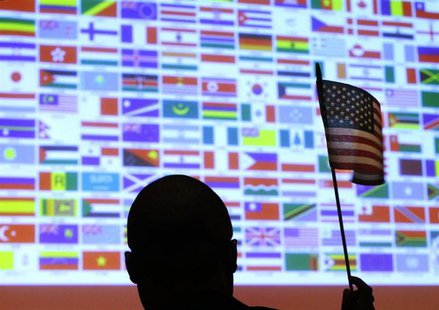 A new U.S. citizen waves a U.S. national flag in front of a display of flags of the more than 40 nations represented by the more than 90 imm A new U.S. citizen waves a U.S. national flag in front of a display of flags of the more than 40 nations represented by the more than 90 imm