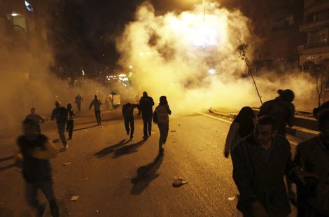 Protesters who oppose Egyptian President Mohamed Mursi flee from teargas released by riot police during clashes along a street which leads t Protesters who oppose Egyptian President Mohamed Mursi flee from teargas released by riot police during clashes along a street which leads t