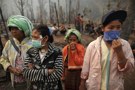 Refugee women and other survivors look on as investigation continues in the ruins of the Ban Mae Surin refugee camp near Mae Hong Son March Refugee women and other survivors look on as investigation continues in the ruins of the Ban Mae Surin refugee camp near Mae Hong Son March