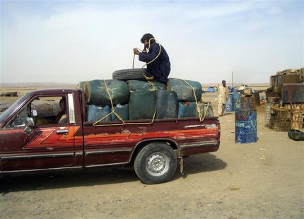 A man sits on top of plastic canisters of petrol that he says was brought from Iran, as he prepares to unload them from a van at a roadside A man sits on top of plastic canisters of petrol that he says was brought from Iran, as he prepares to unload them from a van at a roadside