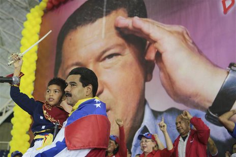 Venezuela's acting President Nicolas Maduro carries a child dressed as national hero Simon Bolivar in front of a poster of late president Hu Venezuela's acting President Nicolas Maduro carries a child dressed as national hero Simon Bolivar in front of a poster of late president Hu