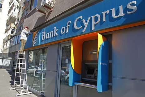A worker paints a wall above a branch of Bank of Cyprus in Bucharest April 1, 2013. REUTERS/Bogdan Cristel A worker paints a wall above a branch of Bank of Cyprus in Bucharest April 1, 2013. REUTERS/Bogdan Cristel