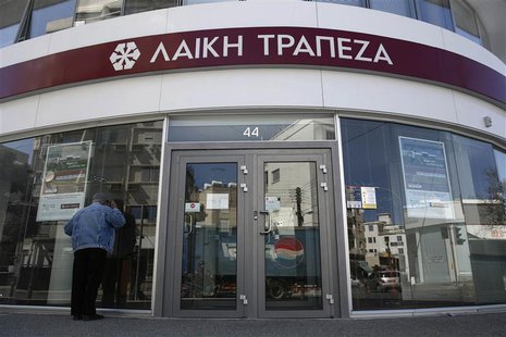 A man tries to look inside a branch of Laiki Bank a few hours before the re-opening of the banks on the island in Nicosia in this March 28, A man tries to look inside a branch of Laiki Bank a few hours before the re-opening of the banks on the island in Nicosia in this March 28,