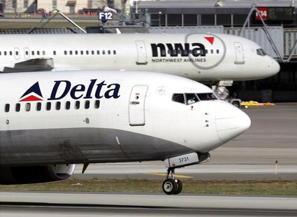 A Delta Air Lines jet takes off past a Northwest Airline jets parked at gates at the Minneapolis St.Paul International Airport in Minneapoli A Delta Air Lines jet takes off past a Northwest Airline jets parked at gates at the Minneapolis St.Paul International Airport in Minneapoli