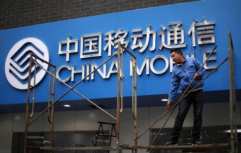 A labourer works in front of a sign for China Mobile at the company's office in downtown Shanghai March 11, 2013. REUTERS/Carlos Barria A labourer works in front of a sign for China Mobile at the company's office in downtown Shanghai March 11, 2013. REUTERS/Carlos Barria