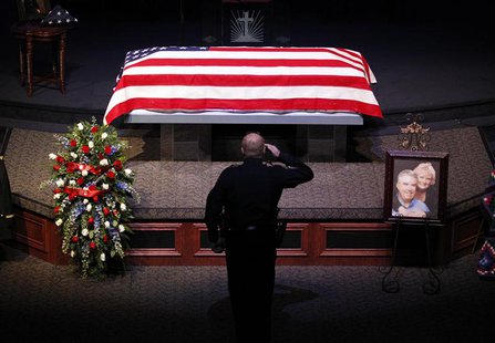 A police officer salutes at a memorial service for Kaufman County district attorney Mike McLelland and his wife Cynthia in Sunnyvale, Texas A police officer salutes at a memorial service for Kaufman County district attorney Mike McLelland and his wife Cynthia in Sunnyvale, Texas
