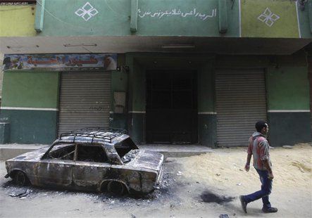 A man walks in front of a burnt car and a house belonging to a Christian after clashes between Muslims and Christians in Khusus, El-Kalubia A man walks in front of a burnt car and a house belonging to a Christian after clashes between Muslims and Christians in Khusus, El-Kalubia