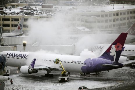 A Hawaiian Airlines plane undergoes de-icing before takeoff at Seattle-Tacoma International Airport in Seatac, Washington January 19, 2012. A Hawaiian Airlines plane undergoes de-icing before takeoff at Seattle-Tacoma International Airport in Seatac, Washington January 19, 2012.