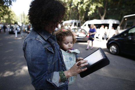 A woman carrying a child looks at an iPad tablet after the Emporio Armani Spring/Summer 2013 collection at Milan Fashion Week September 20, A woman carrying a child looks at an iPad tablet after the Emporio Armani Spring/Summer 2013 collection at Milan Fashion Week September 20,